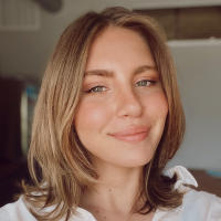 A young woman smiling. She’s wearing a casual white shirt and has strawberry blonde hair.